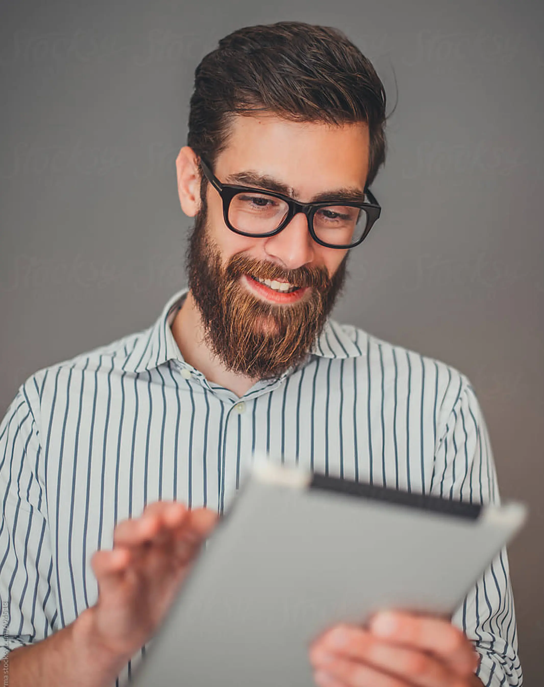 Homem sorrindo, olhando para um tablet