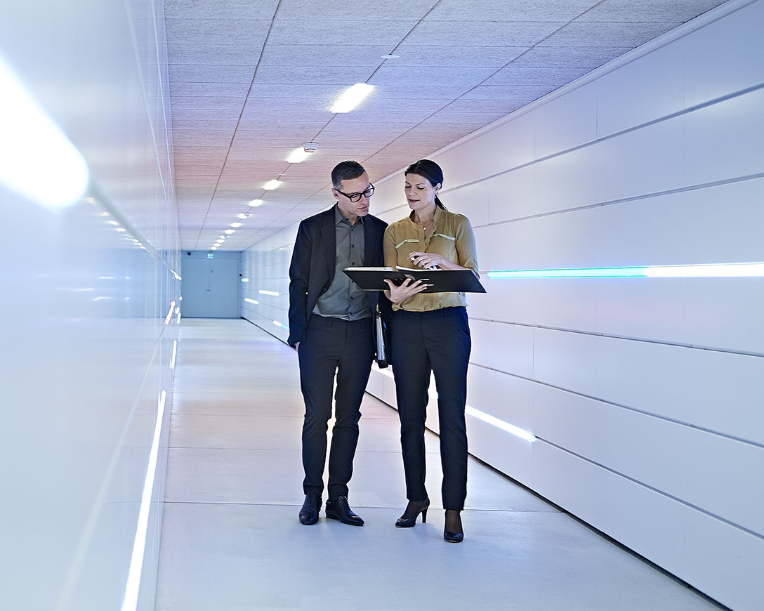 Best In Class - two colleagues discuss details in a sleek, ultramodern corridor