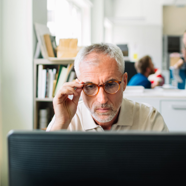 Un homme portant des lunettes, respirant l'intelligence et la sophistication, regarde au loin avec assurance.