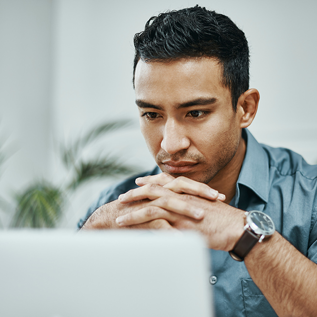 Un uomo concentrato sullo schermo del suo computer portatile