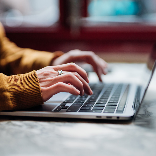 Le mani di una persona che digitano con determinazione su un computer portatile