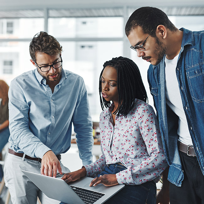 Três colegas de trabalho analisam e discutem dados em um laptop