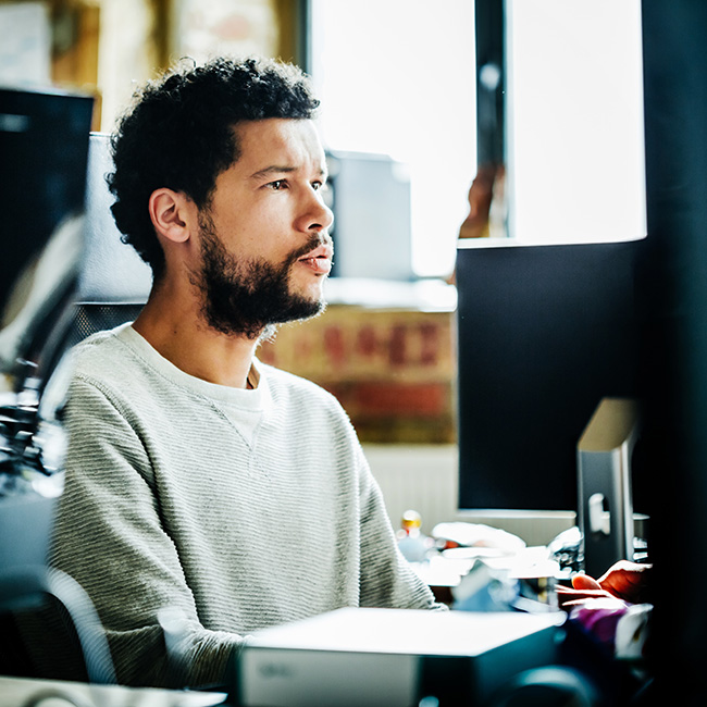 Retrato de joven empresario informal trabajando en un ordenador