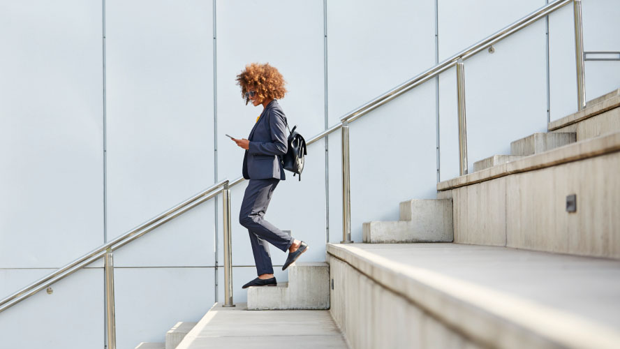 Une femme en costume d'affaires montant gracieusement une volée de marches, respirant la confiance et le professionnalisme.