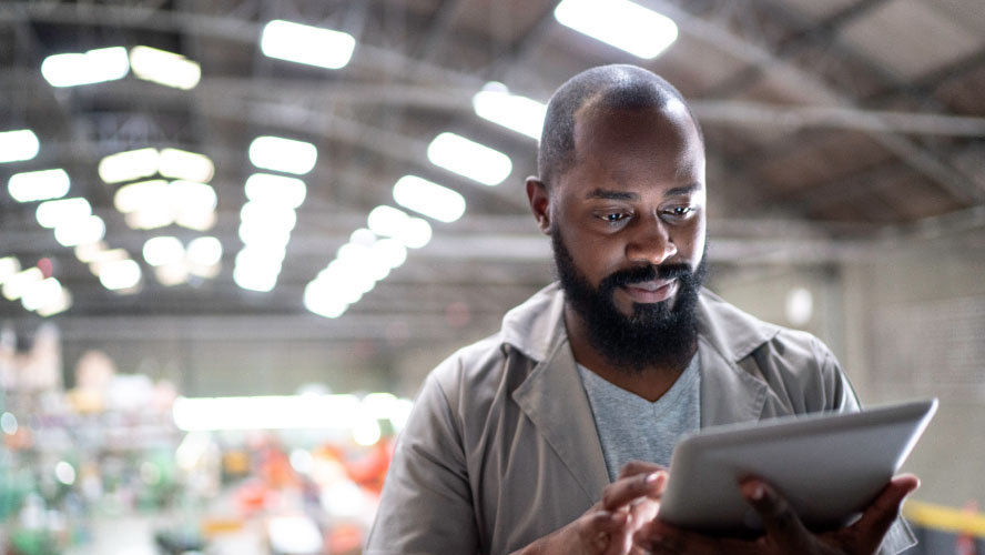 A bearded man engrossed in using a tablet device, displaying focused attention and technological engagement.