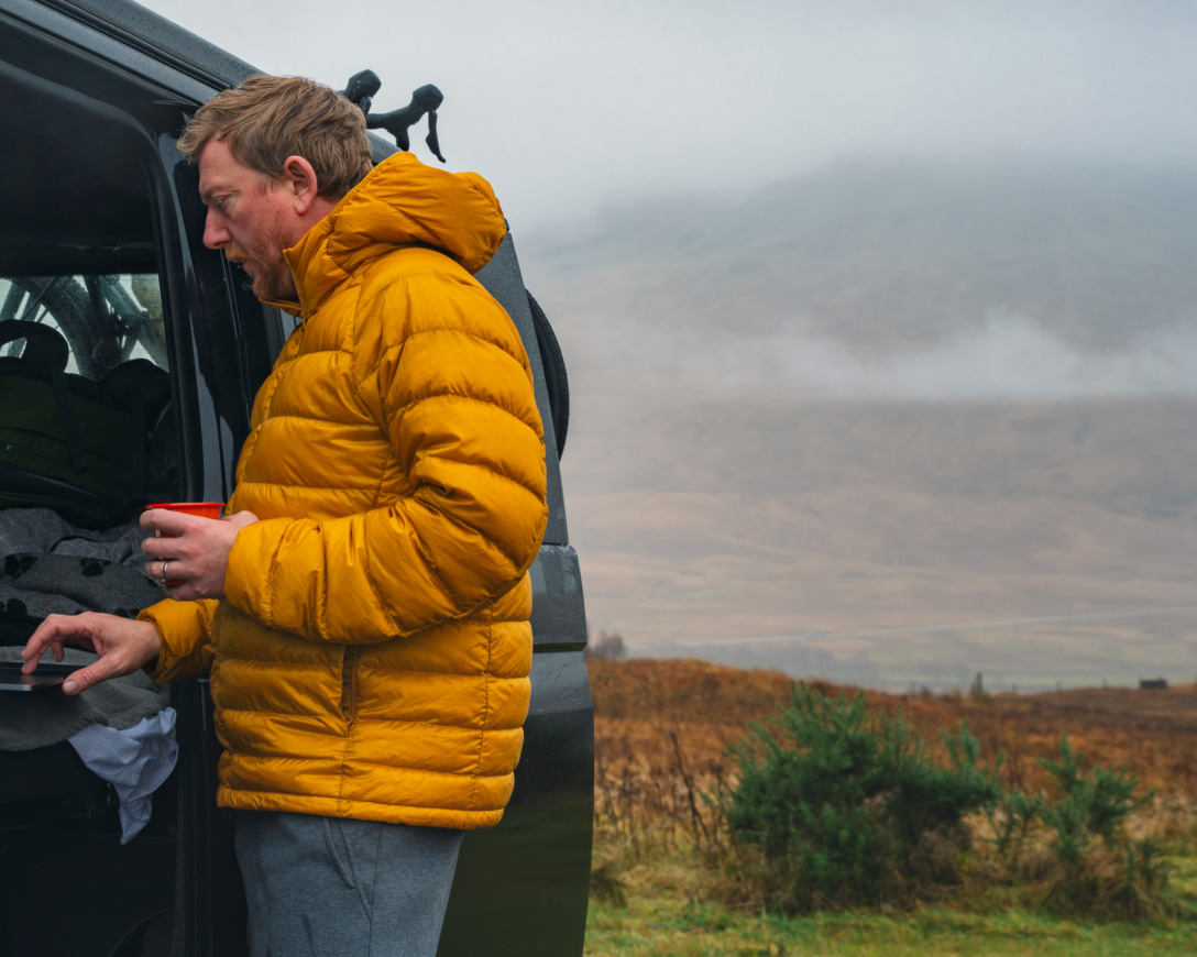 A man in a yellow jacket opens a van door.