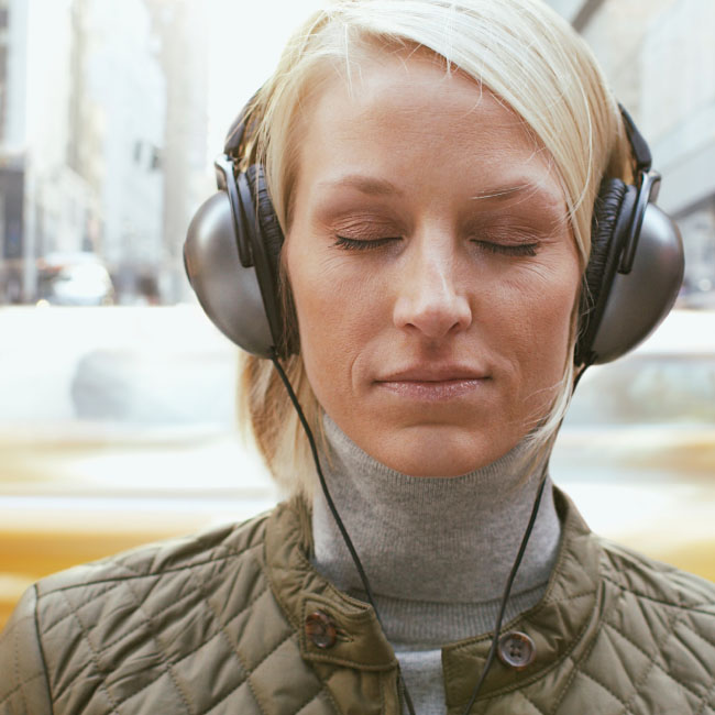 Une femme portant des écouteurs, absorbée par sa musique, profitant d'un moment de bonheur auditif.