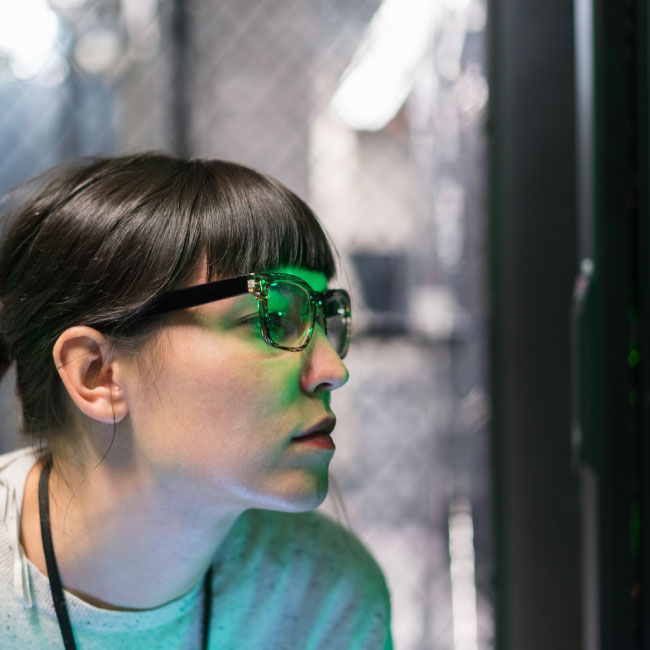 Une femme à lunettes concentrée sur un écran d'ordinateur, absorbée par son travail.