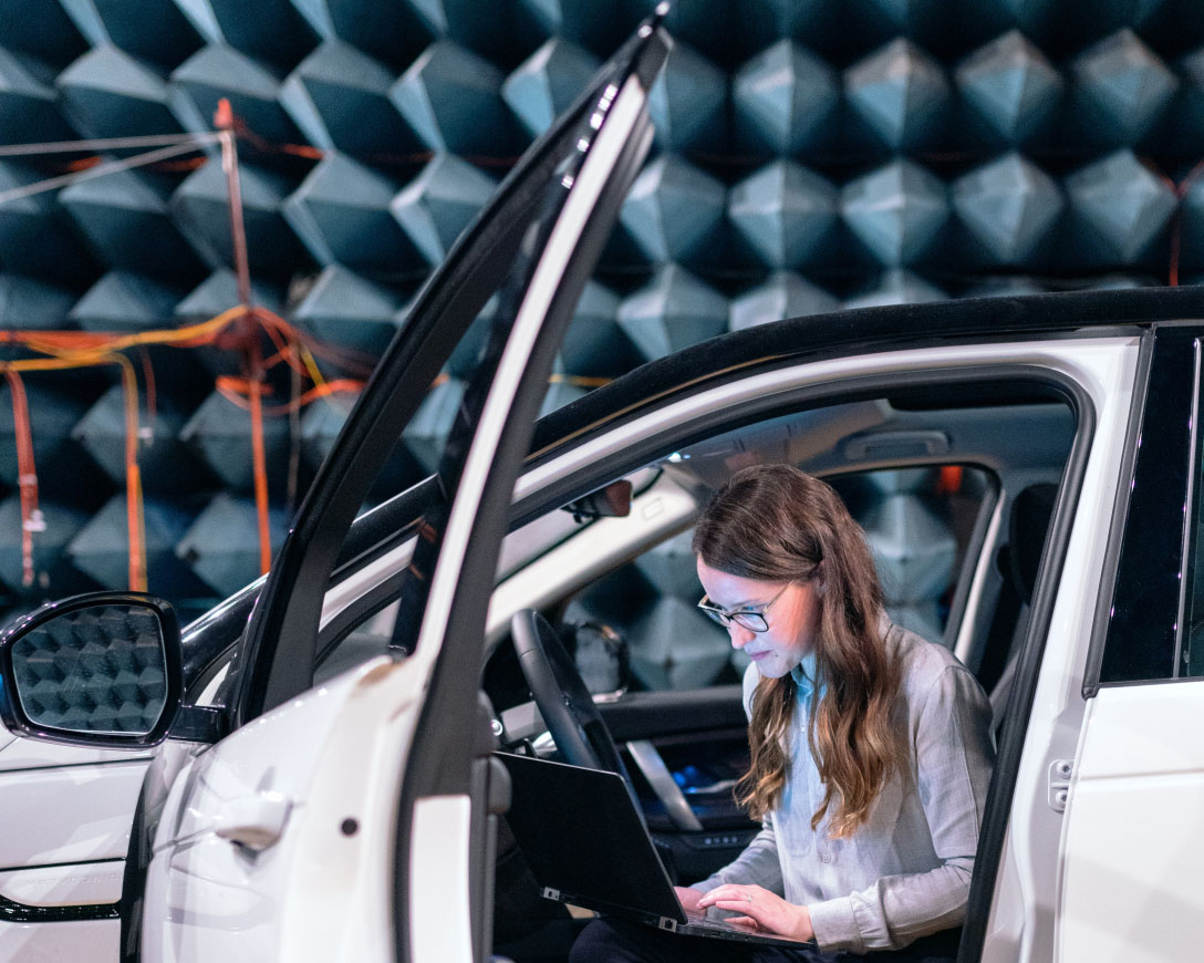 Une femme sur le siège conducteur d&#039;une voiture, concentrée sur son ordinateur portable.