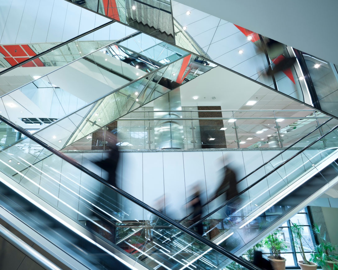 A group of individuals descending on an escalator, moving in unison towards their destination.